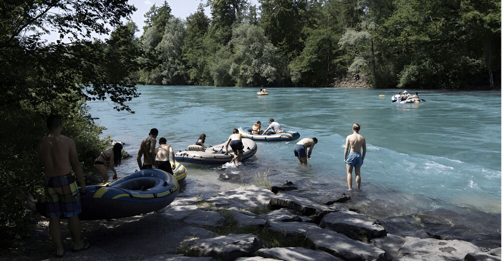 People in inflatable rafts on a river surrounded by trees. 4