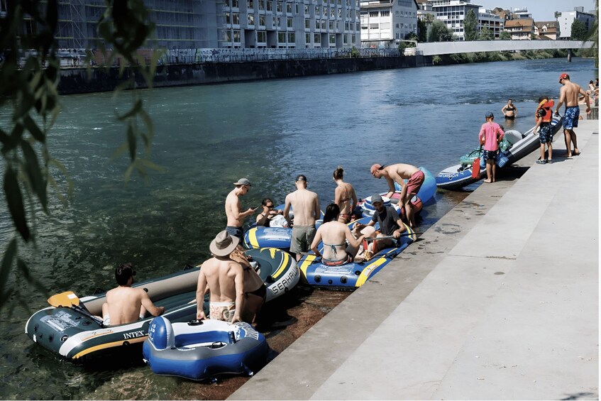 People preparing to raft on a river, with inflatable boats lined up at the dock. 5