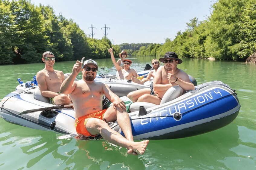 A group of people on a blue and white inflatable boat named 'Excursion 4' on a river surrounded by greenery. 1