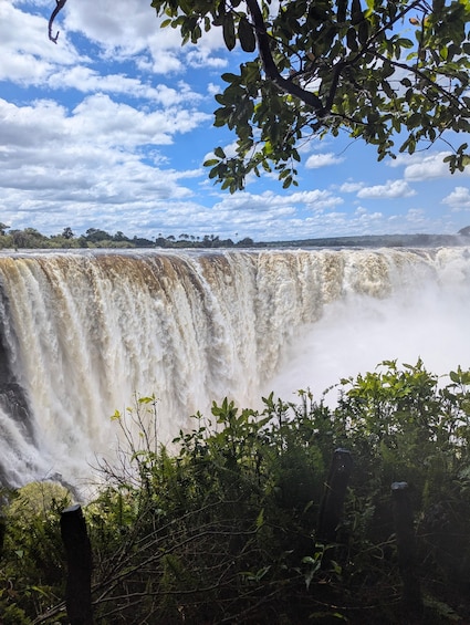 A waterfall with a forested foreground and a clear sky. 2