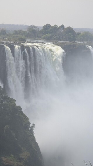 A large waterfall cascading over a cliff, surrounded by dense greenery. 3