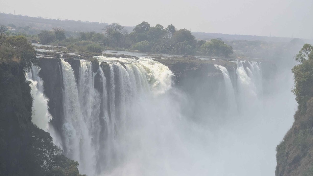 A large waterfall cascading down a cliff surrounded by dense vegetation. 5
