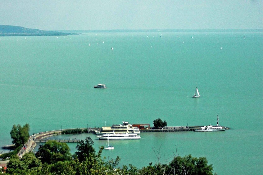 A calm sea with boats, a pier, and a distant shoreline. 1