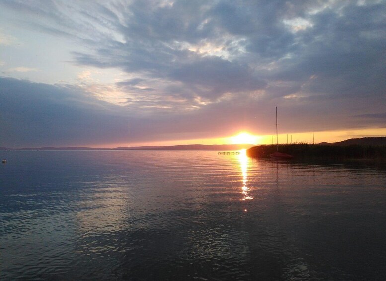 A sunset over a calm body of water with a distant shoreline and a clear sky. 3