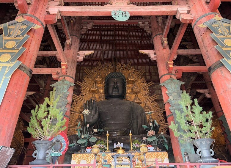 A large Buddha statue in a temple with intricate architecture and offerings. 1