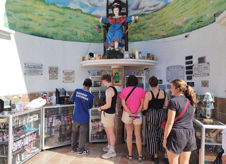 A mural of a woman in blue and red, a man in a blue shirt, and several people standing at a counter with various items displayed. 2