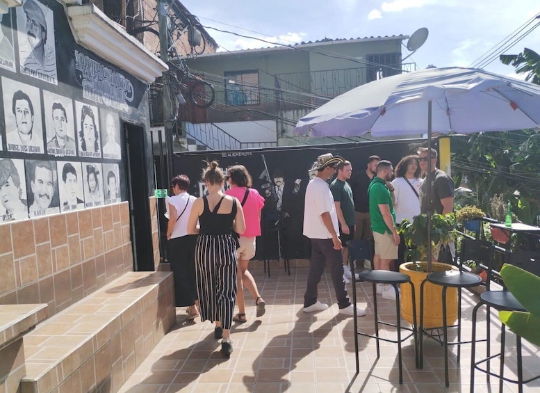 A courtyard with tiled flooring, a mural with portraits, outdoor seating, and a large umbrella. 3
