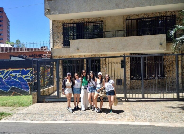 A group of people posing in front of a building with a stone facade and metal gates. 5