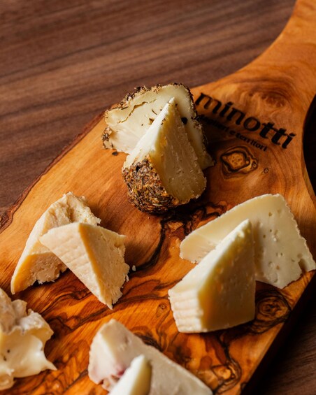 A wooden cutting board with cheese and garlic slices. 3