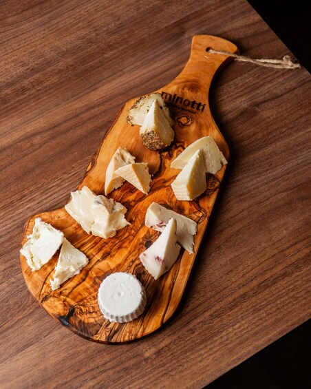A wooden cheese board with various cheese cuts and a salt shaker. 4