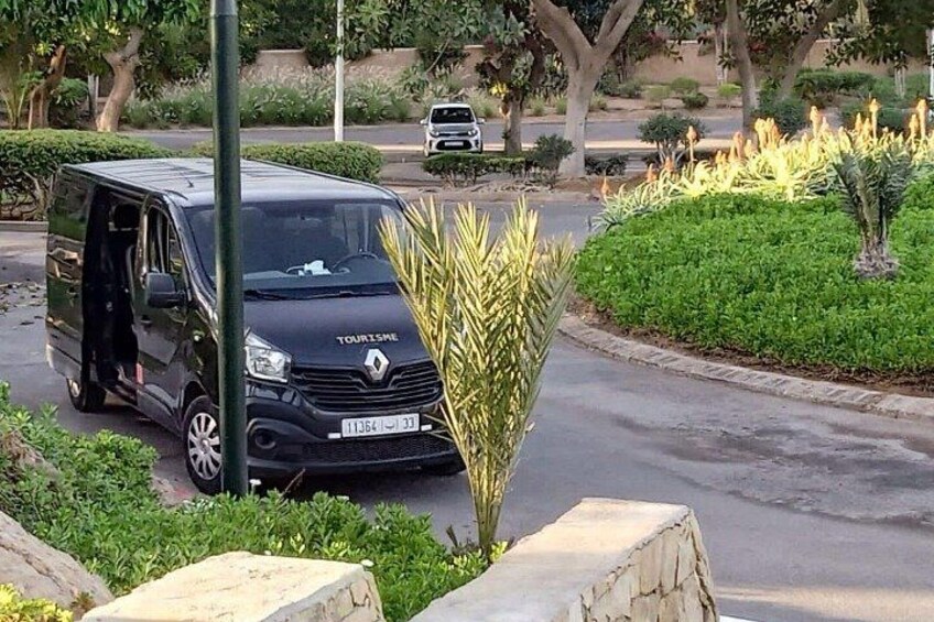A black Renault Touran van parked on a street with greenery and a stone structure nearby. 2