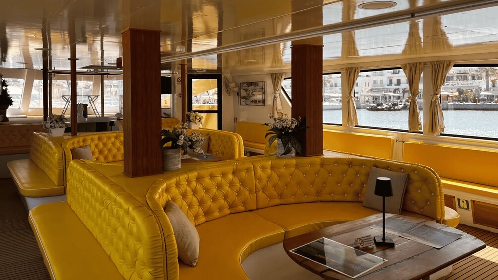 A yellow upholstered sofa set in a modern interior with large windows overlooking a waterfront. 2