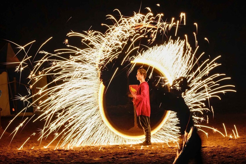 A person performing a firework act with sparks flying around. 1