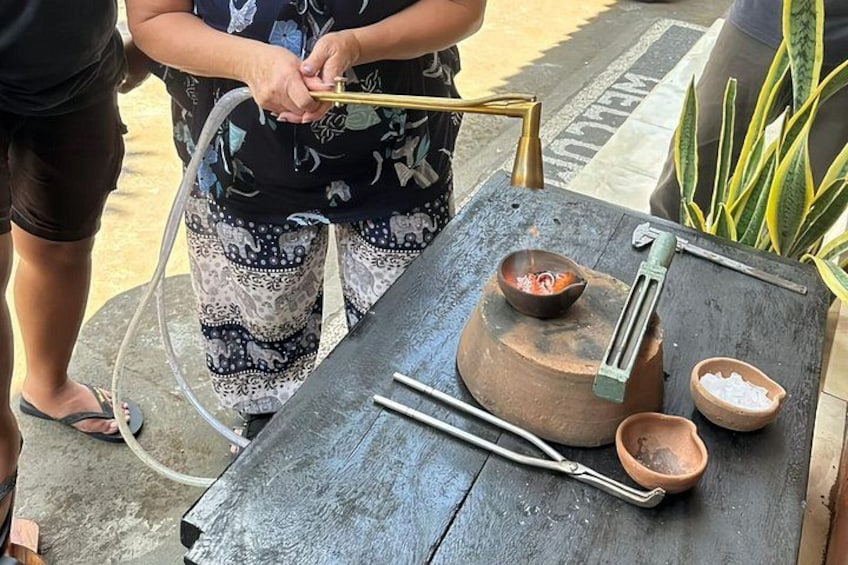 Una persona usando una bomba de agua manual, un mortero y una mazo, y un cuenco pequeño sobre una mesa de madera. 5
