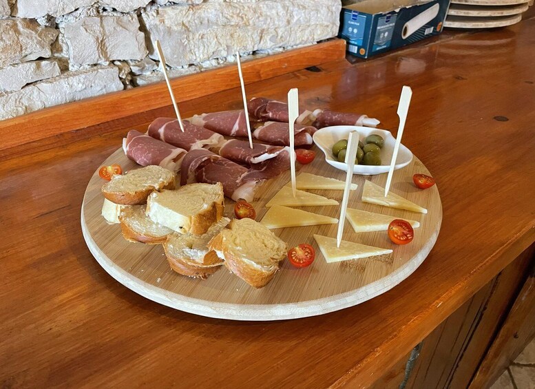 A charcuterie board with various meats, cheeses, and olives on a wooden table. 2
