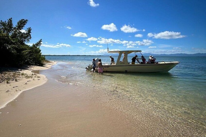 A boat on a beach with people on board, a clear sky, and calm water. 2