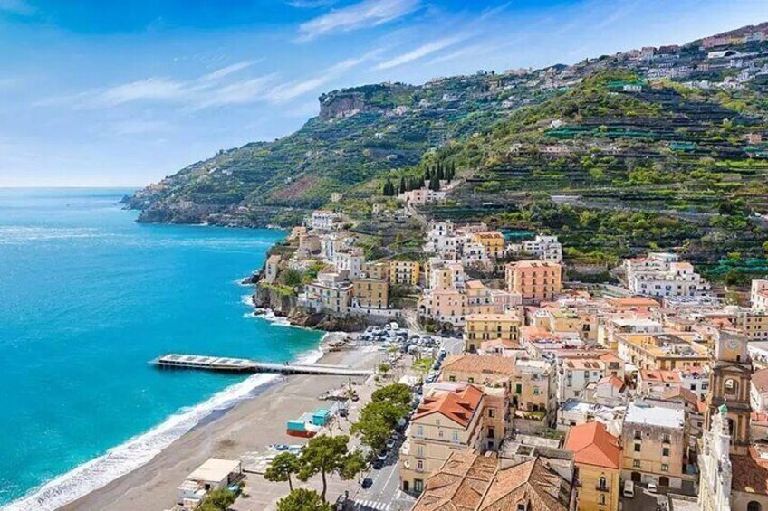 A coastal town with terraced buildings, a beach, and a pier. 4