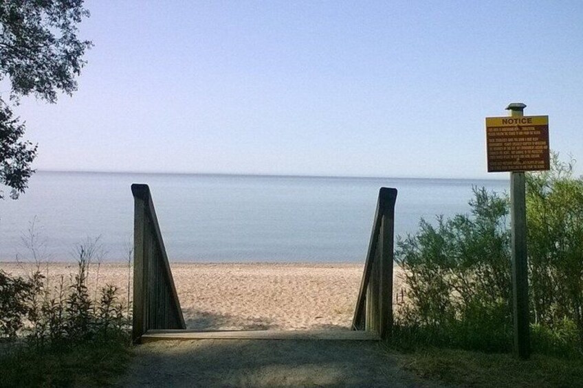 A beach entrance with a wooden gate and a notice sign. 1