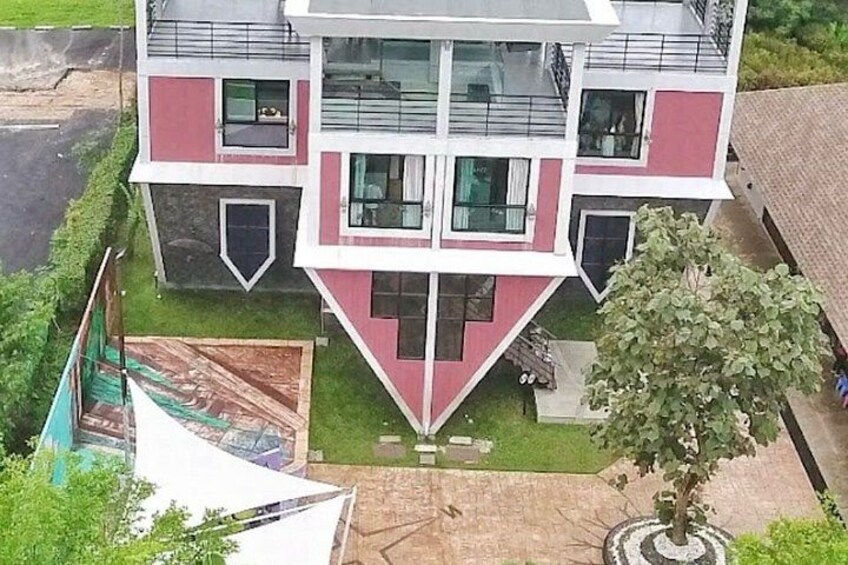 A multi-story building with a red and white facade, a small garden, and a tree in front. 3