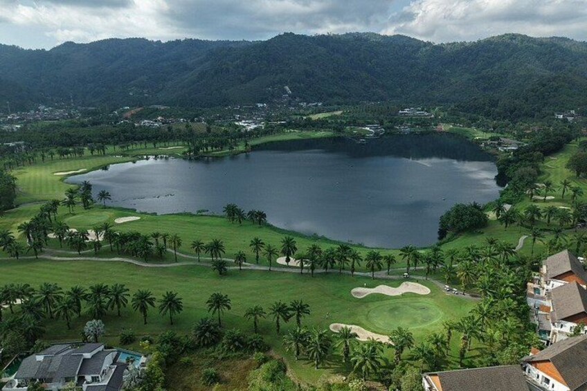 A golf course with a large lake, surrounded by palm trees and mountains. 5