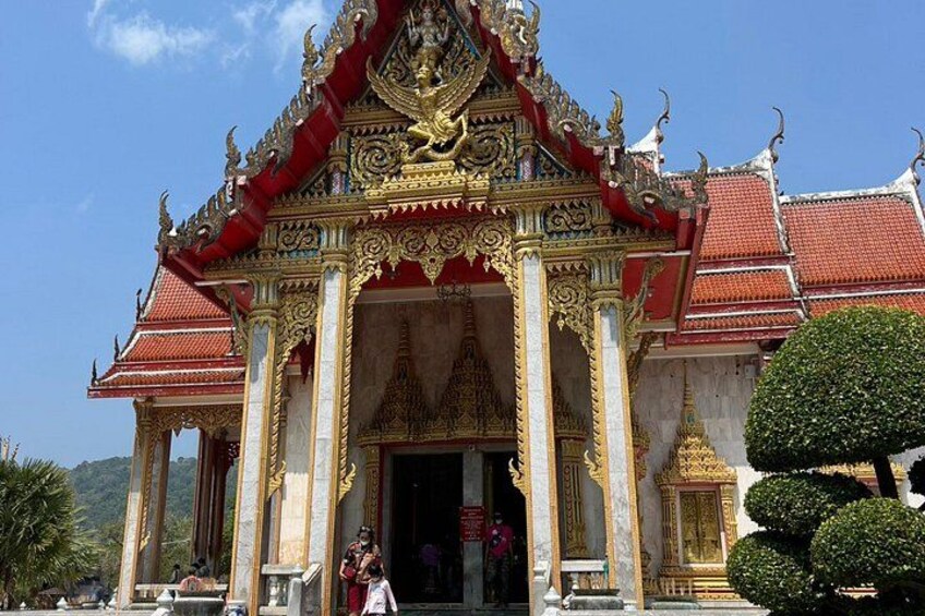 A temple with ornate golden and red decorations, a large central entrance, and a bell tower. 4