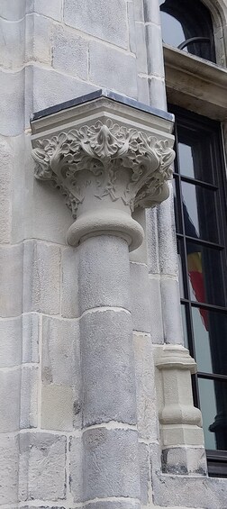 A stone column with intricate carvings and a window with a reflection. 5