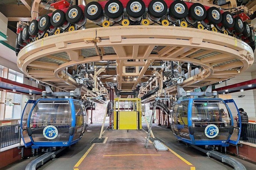 Sistema de teleférico con dos cabinas azules sobre vías, cables aéreos y una barrera de seguridad amarilla. 5