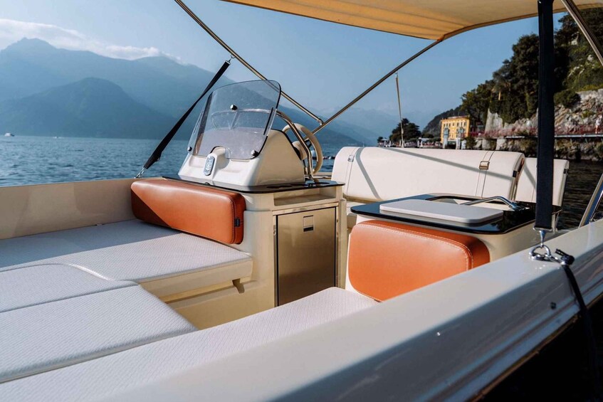 A boat's interior with cushioned seating, a steering wheel, and a small storage compartment. 3
