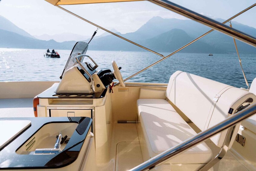 A boat's interior with a steering wheel, control panel, and cushioned seating. 2