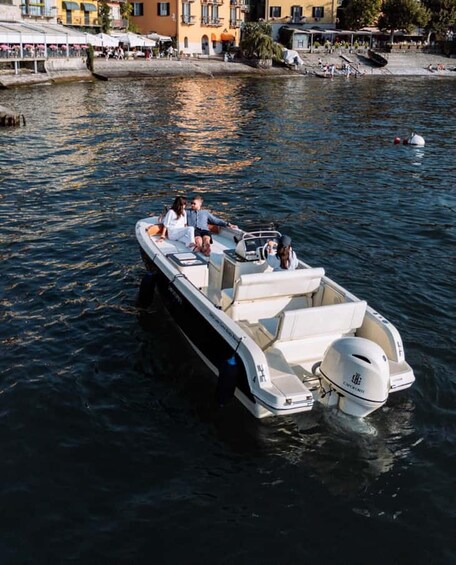 A small motorboat with passengers on a calm river, surrounded by buildings and a dock. 5