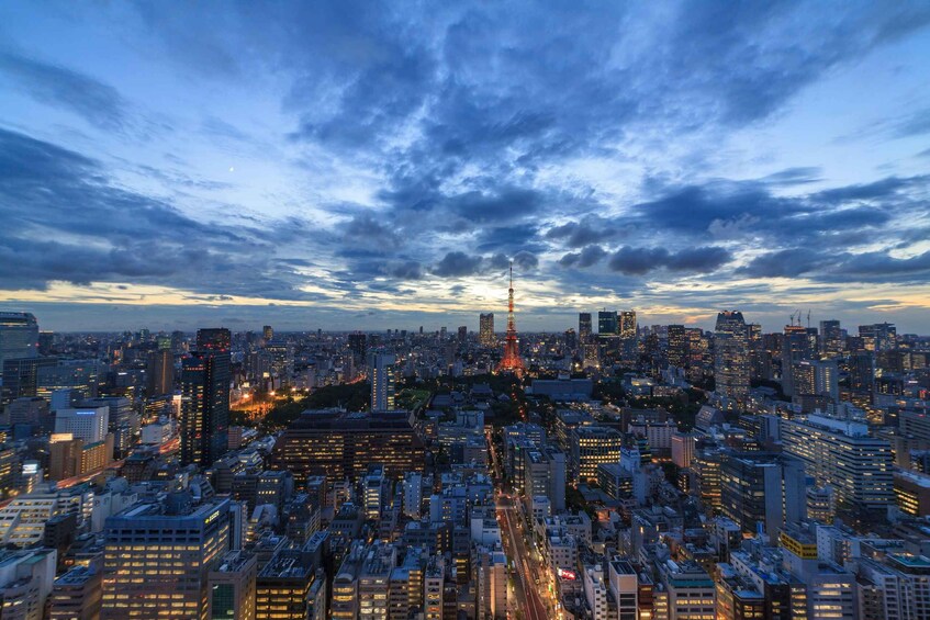 A cityscape at dusk with a prominent tower and dense urban buildings. 1