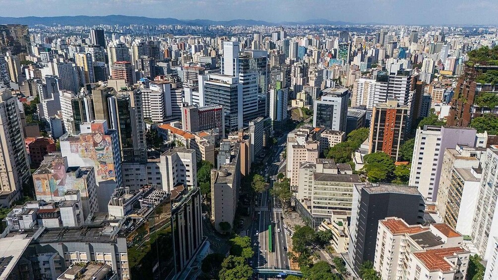 A densely packed urban landscape with numerous high-rise buildings, a central road, and distant hills. 3