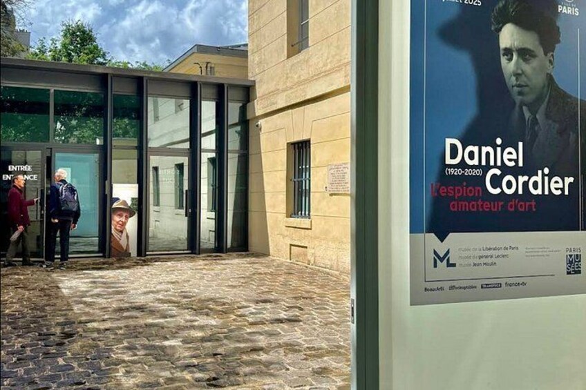 L’entrée d’un bâtiment avec des portes vitrées et une affiche annonçant une exposition d’art. 2