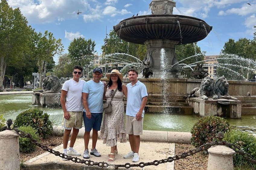 En grupp människor som står framför en fontän med vattenstrålar. 3