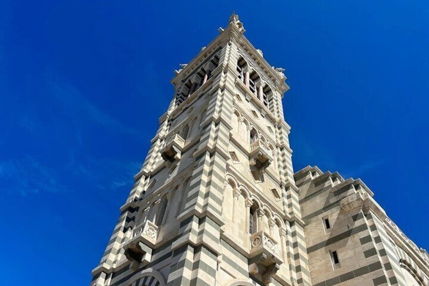 Una torre alta y ornamentada con detalles arquitectónicos elaborados contra un cielo azul despejado. 1