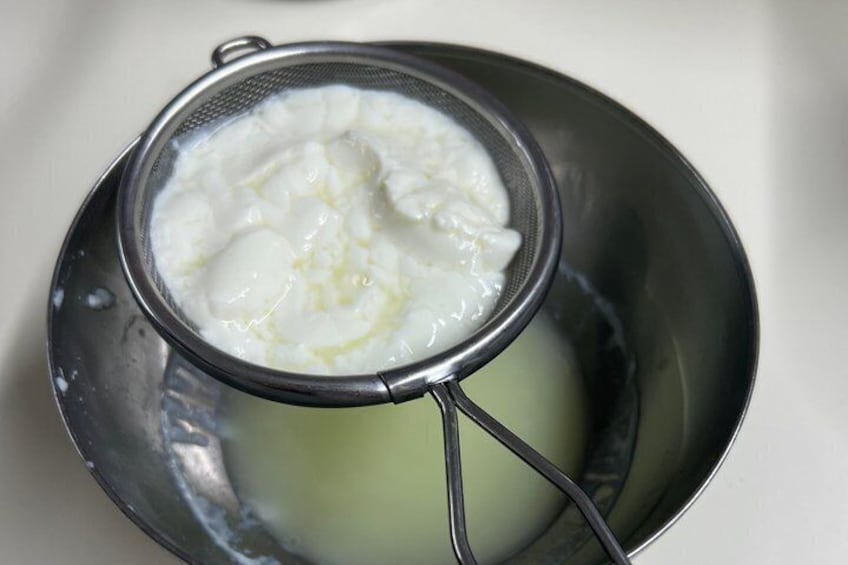A metal strainer over a bowl containing a white liquid, possibly yogurt or cream. 5