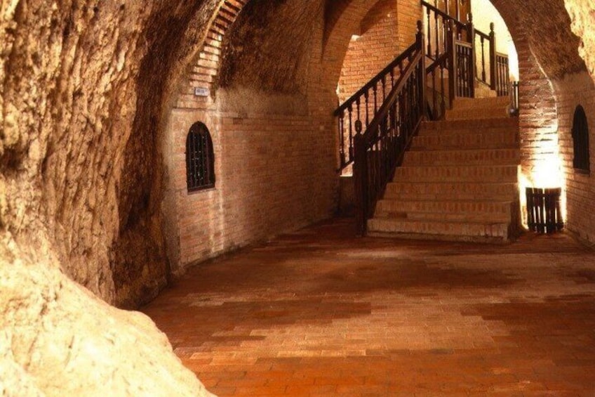 An underground stone corridor with a staircase and arched brick walls. 3