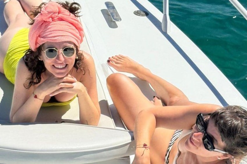 A boat with two people lying on the deck, one wearing a yellow swimsuit and the other in a striped swimsuit. 5