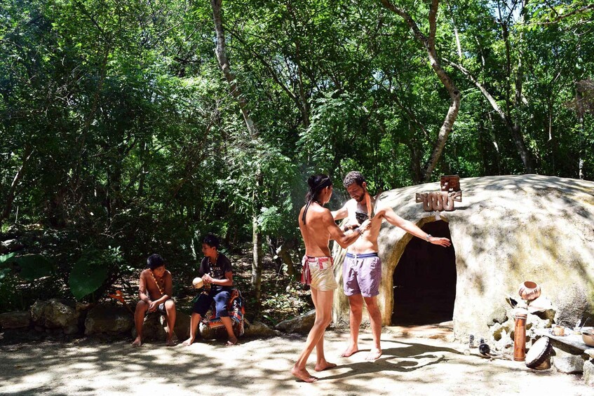 People interacting with a stone structure in a forested area. 1