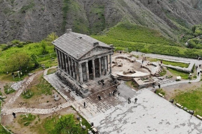 An ancient temple with columns, ruins, and a mountainous backdrop. 4