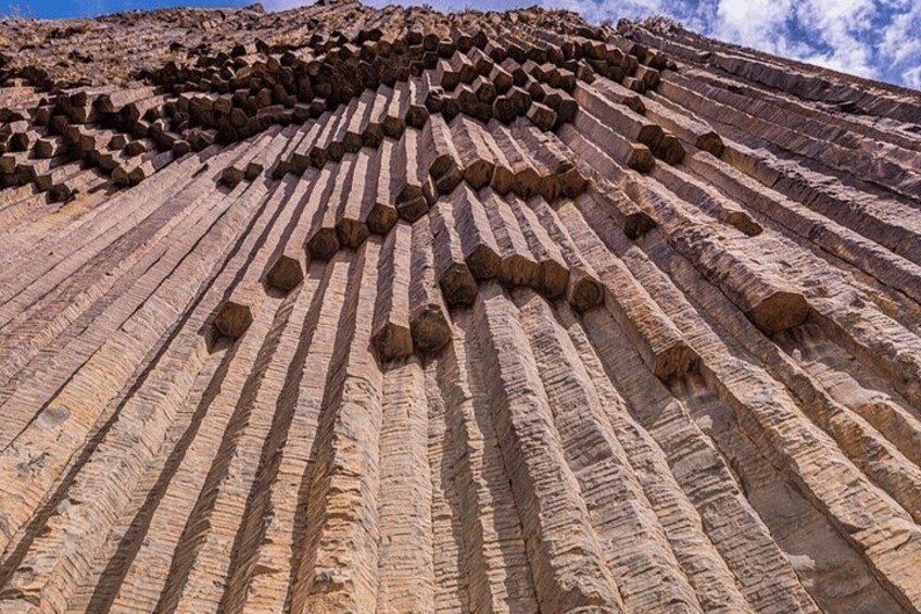 A large rock formation with horizontal striations and numerous hexagonal holes. 2
