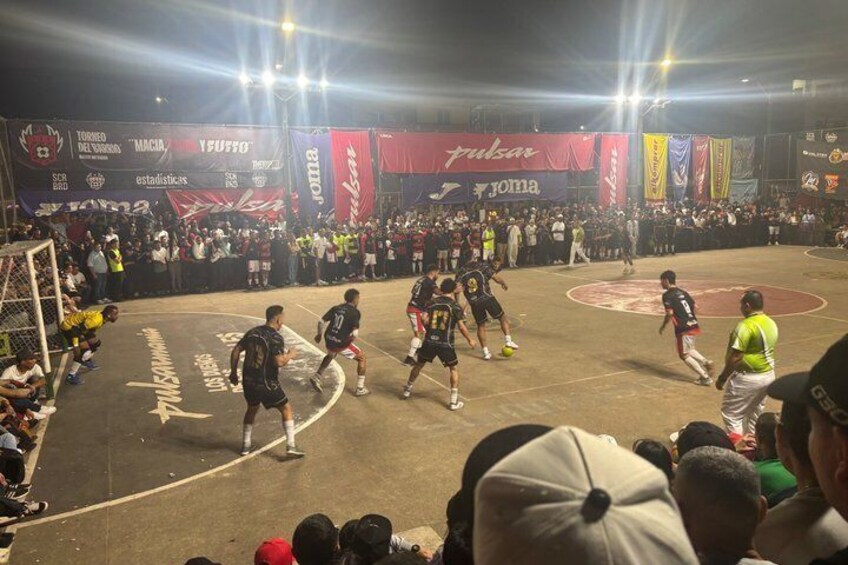 A basketball game in progress with players on the court, a crowd in the background, and banners hanging around the arena. 4