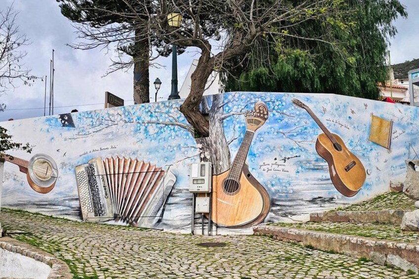Une fresque représentant des instruments de musique, un arbre et un chemin pavé. 1