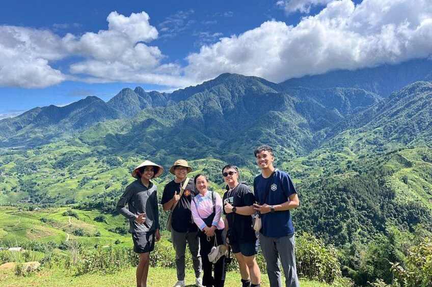 A group of people standing on a hill with a mountainous landscape in the background. 1
