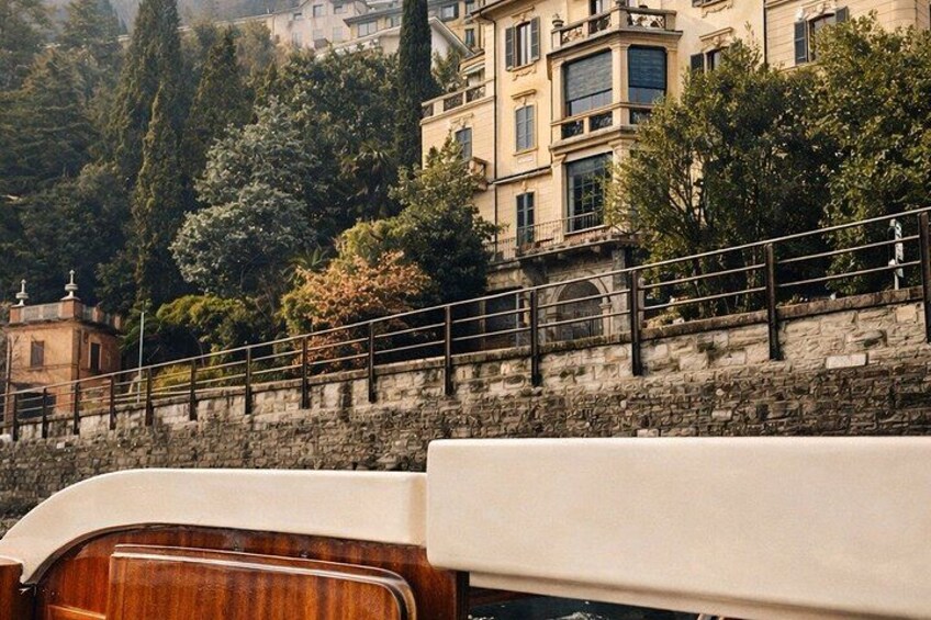 A stone wall with a railing, a wooden boat, and a building with multiple windows in the background. 3