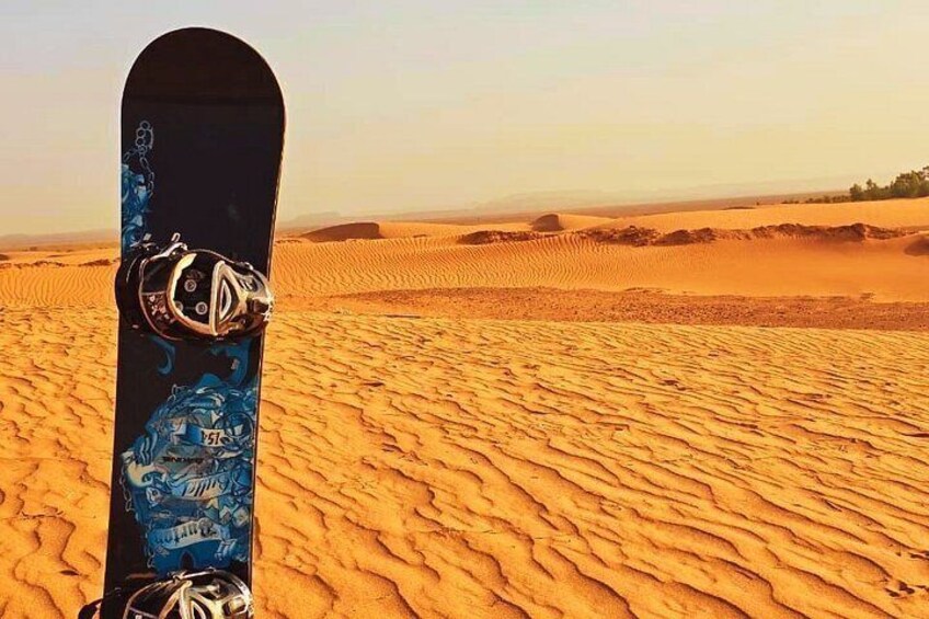 A snowboard in a desert with sand dunes. 2