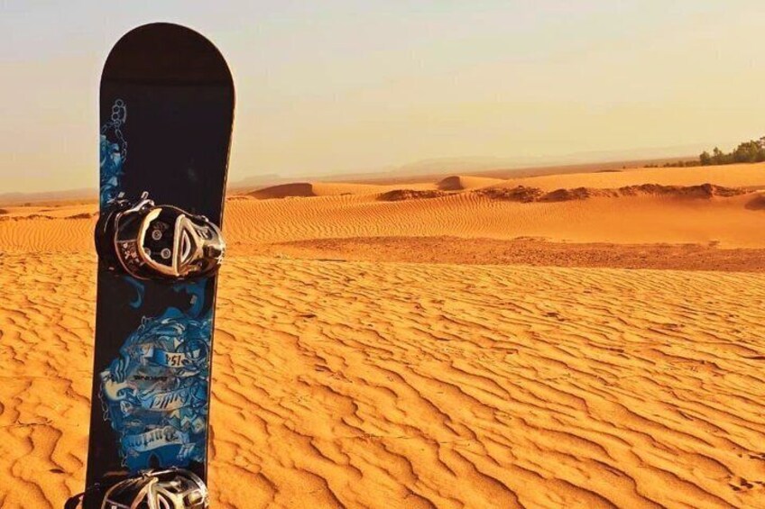 A snowboard in a desert with sand dunes. 2