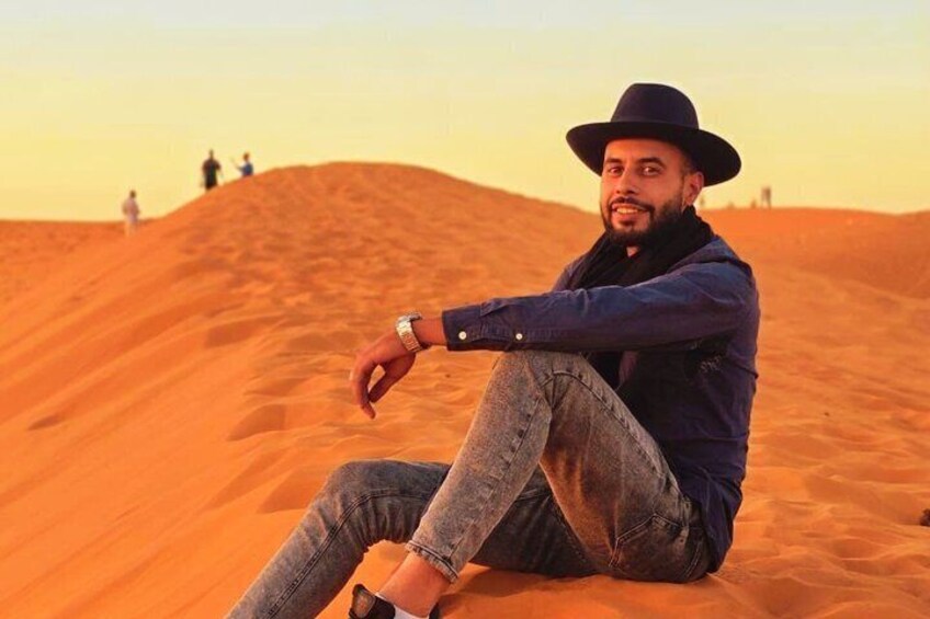 A person sitting on a sand dune in a desert landscape. 5