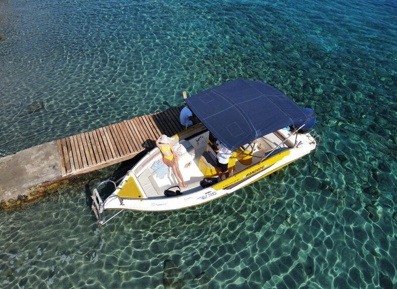 A small boat with a canopy, docked at a pier with clear water. 5