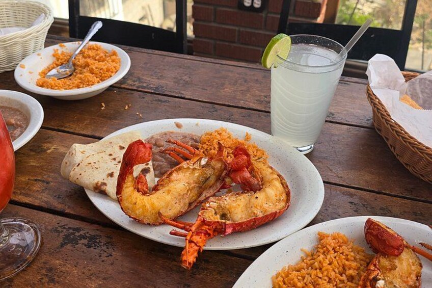Un homard sur une assiette, un verre de thé glacé et un panier de pain sur une table en bois. 4
